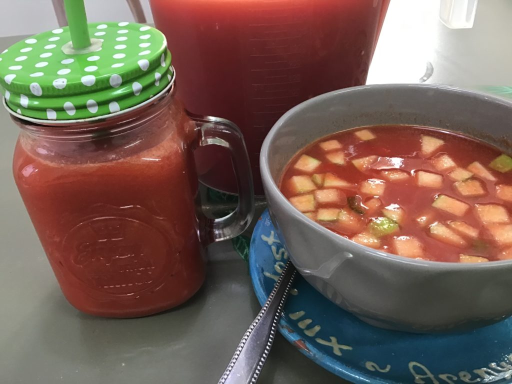 Se aprecia una jarra de servir repleta de gazpacho andaluz, tambien una jarrita individual para tomarlo con cañita y un cuenco al que le he puesto topping de manzana ácida cortada a cuadraditos pequeños.