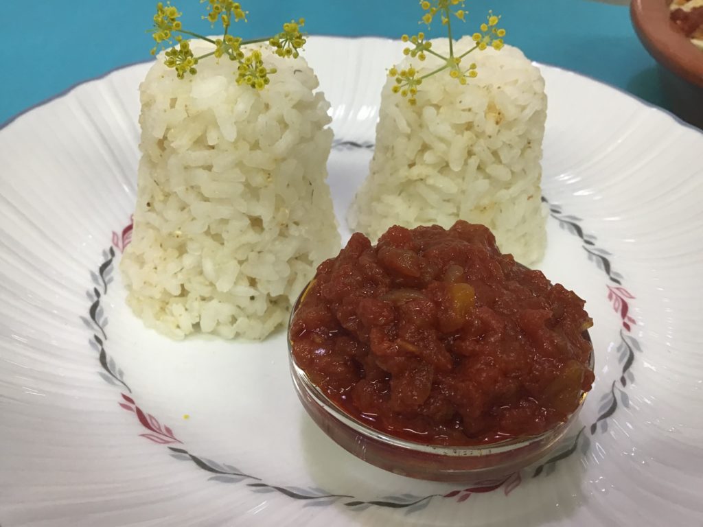 Plato con dos montoncitos de arroz hervido y una pequeña salsera que contiene el tomate frito sin azúcar añadida.