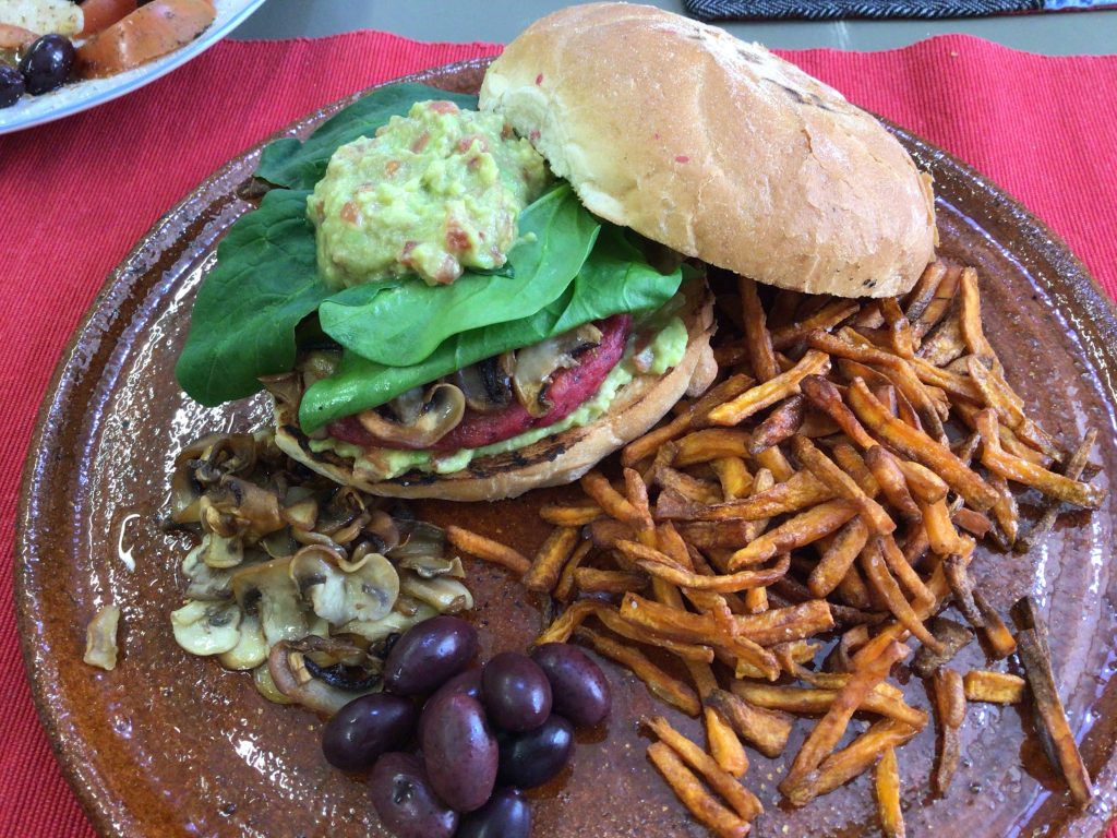 Imagen del superplato con el bocadillo de hamburguesa de garbanzos y curry, champiñones salteados, olivas negras y chips de moniato.